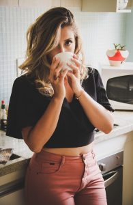 woman wearing black top holding white cup